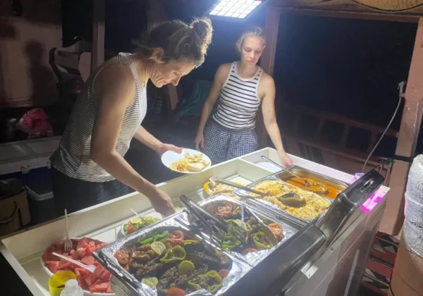 Guests serving BBQ dinner on deck during the Musandam overnight dhow cruise